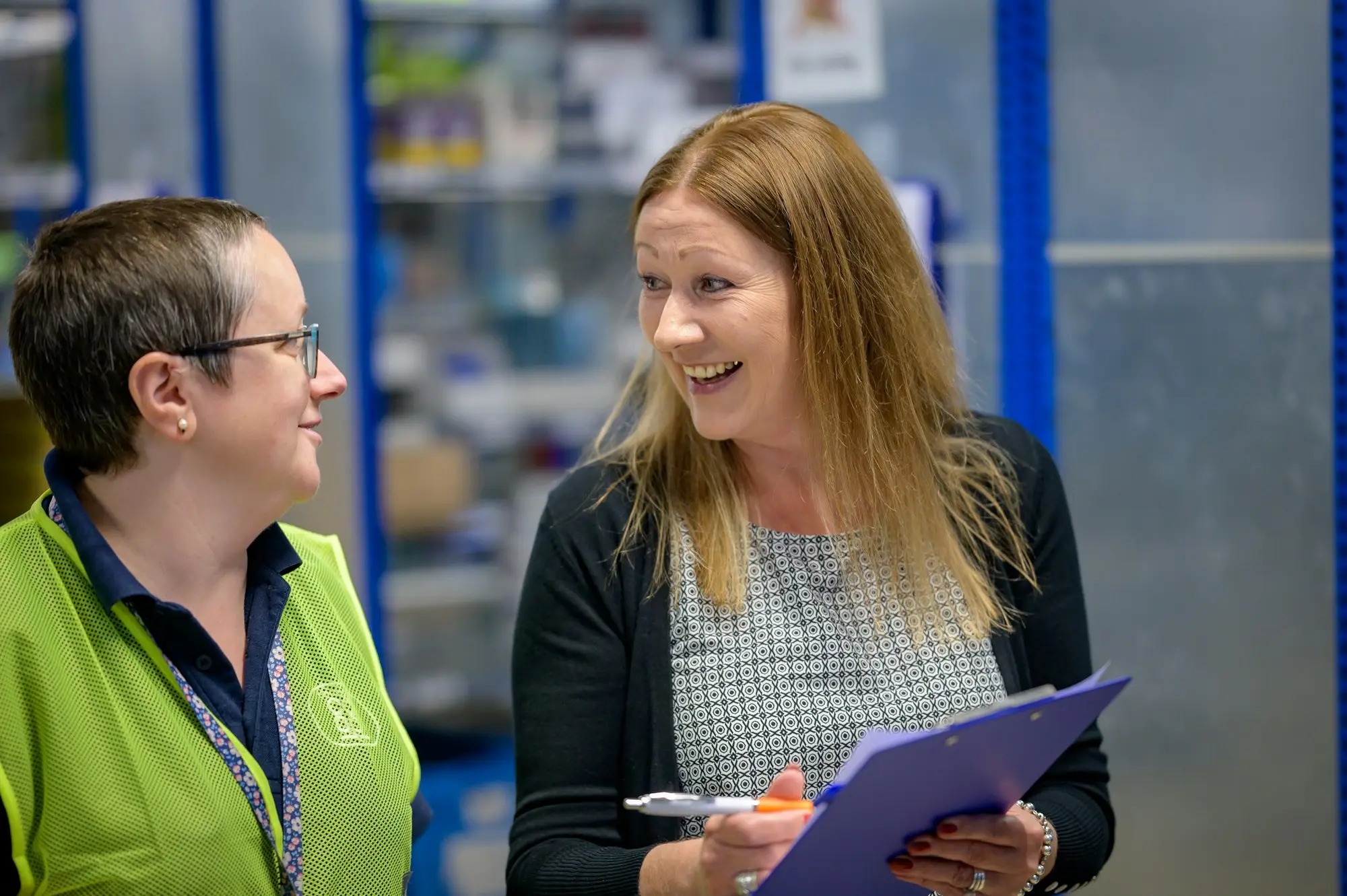 Warehouse manager and adviser smiling while planning over a clipboard